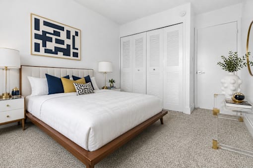A bedroom with a white bed and a black and white abstract painting above it.