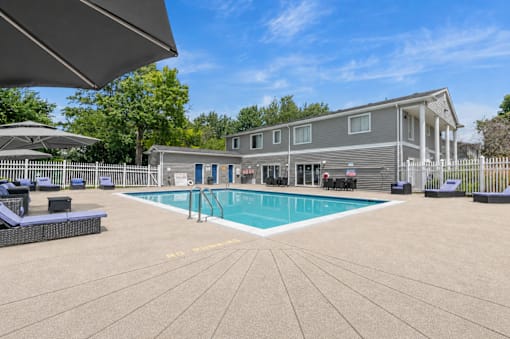 A large outdoor swimming pool with a sun lounger and umbrella.