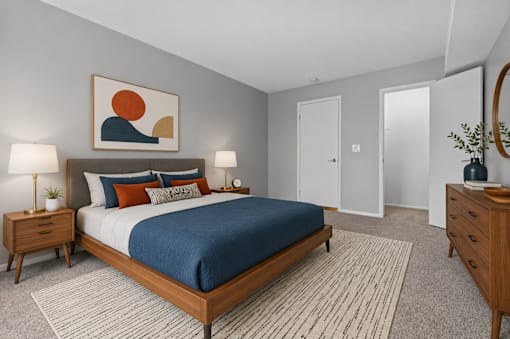 A bedroom with a bed, nightstands, and a painting on the wall.