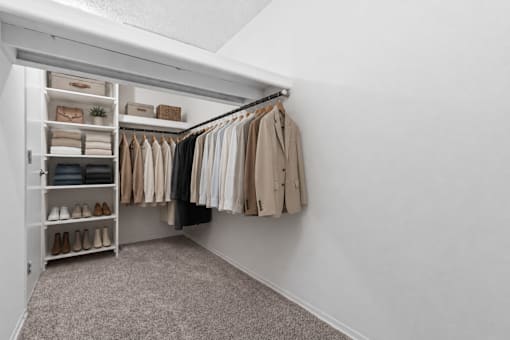 A white closet with clothes and shoes.