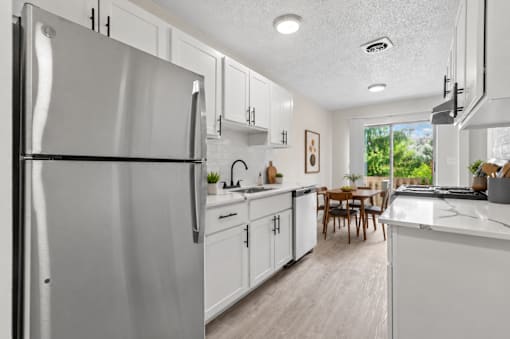 A modern kitchen with white cabinets and a large refrigerator.