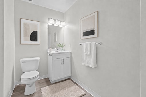 A white toilet sits next to a white cabinet with a mirror above it.