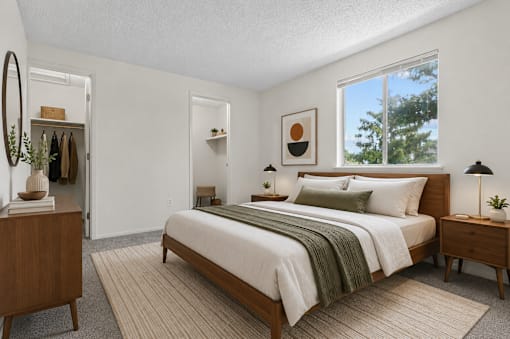 A bedroom with a large bed, a dresser, and a window with a view of trees.