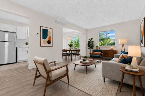 A modern living room with a white refrigerator, a wooden chair, a grey sofa, and a painting on the wall.