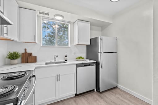 A kitchen with white cabinets and a stainless steel refrigerator.