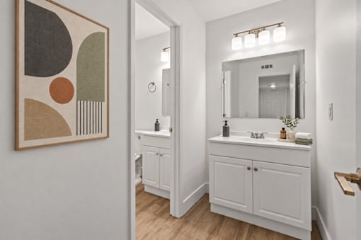 A bathroom with a white cabinet and a mirror above it.