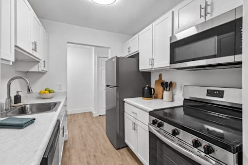 A kitchen with a black refrigerator and stove top oven.
