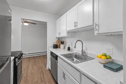 A modern kitchen with a stainless steel refrigerator, a sink, and wooden flooring.