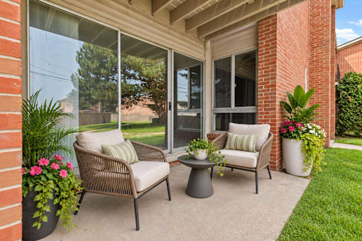 A patio with a chair, table, and potted plants.