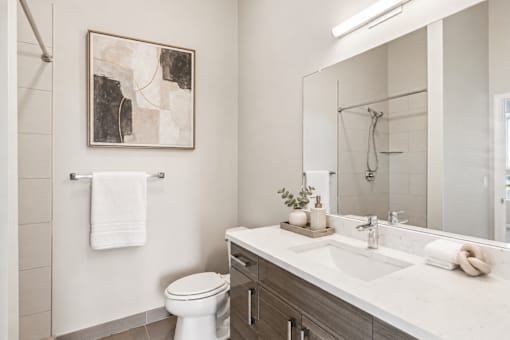 A bathroom with a toilet, sink, and a painting on the wall.