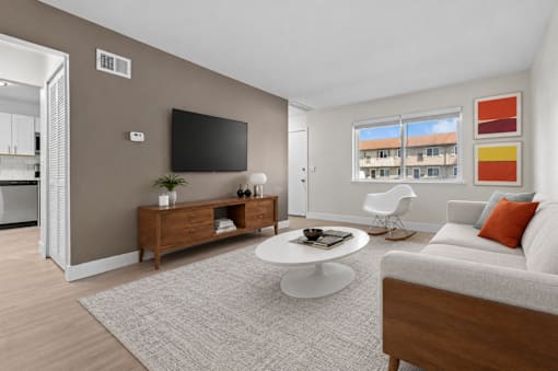 A living room with a grey sofa, a white coffee table, and a flat screen TV mounted on the wall.