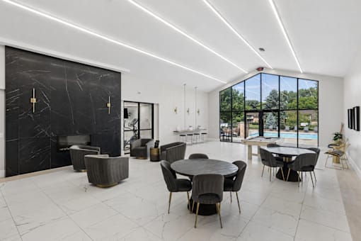 A modern dining room with a black marble wall and a glass table.
