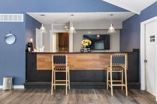 A blue wall with a wooden bar and two chairs.