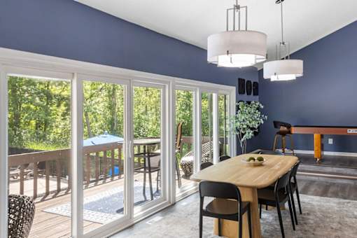 A dining room with a table set for two and a view of the backyard.