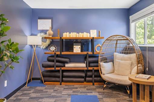 A room with a blue wall and a chair with a white cushion.