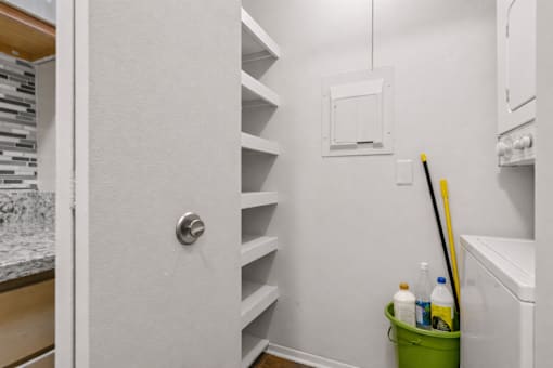 A white door with a silver handle is open to a hallway with a green bucket on the floor.