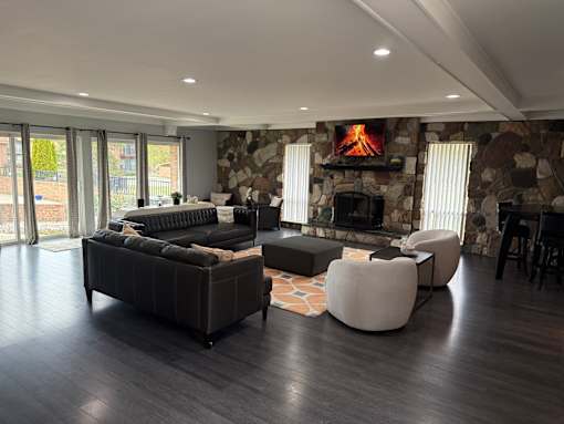 A modern living room with a stone fireplace and dark wood floors.