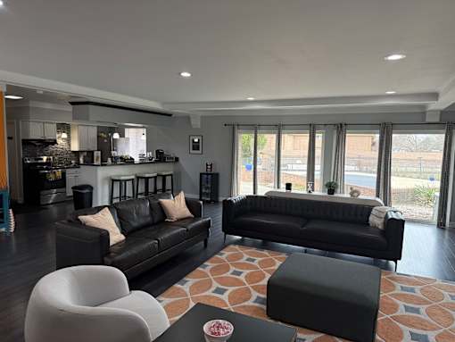 A modern living room with black leather sofas and a white chair.