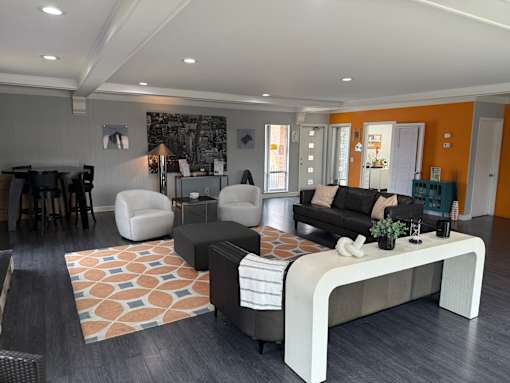 A modern living room with a black couch, a white chair, and a coffee table.