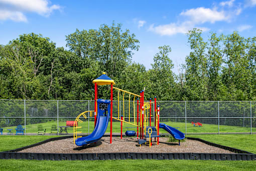 A playground with a yellow and blue slide and a green slide.