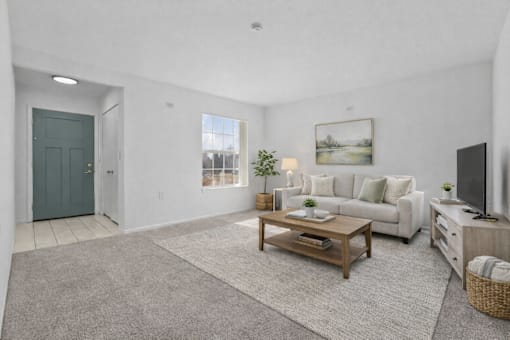 A living room with a white couch, a coffee table, and a television.