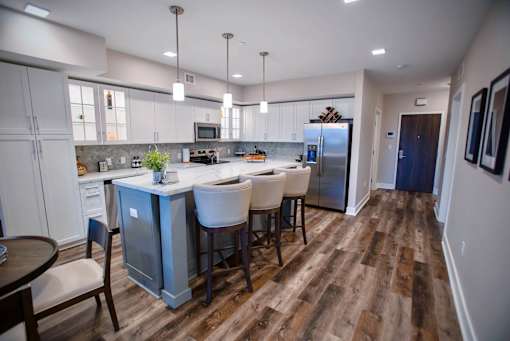 a kitchen with a large island with chairs and a refrigerator