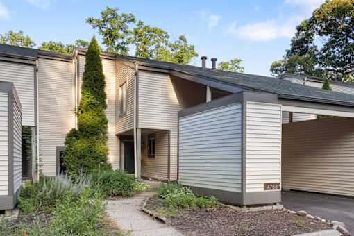 A modern house with a grey exterior and a driveway leading to a garage.