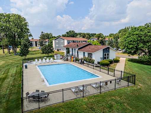A pool surrounded by a black fence with a house in the background.