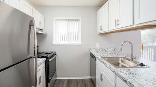 A kitchen with a stainless steel refrigerator and white cabinets.