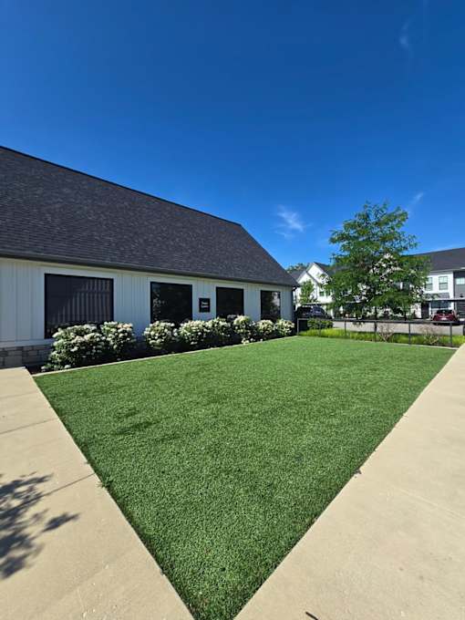 A building with a grey roof and white walls with a green lawn in front.