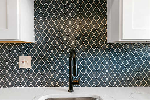 A kitchen sink with a black faucet and a tile backsplash at The Park on 13 Apartments - Royal Oak, MI Apartments, Royal Oak