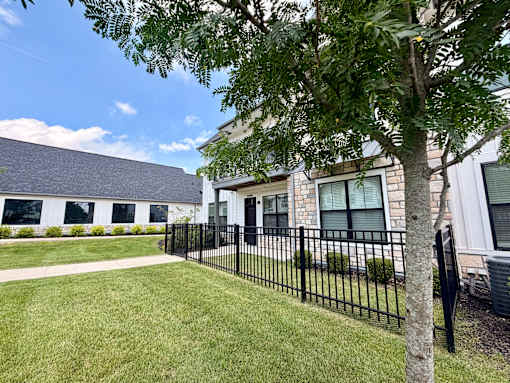 A black metal fence surrounds a grassy area in front of a building.