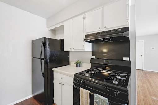 A black stove and refrigerator in a kitchen with white cabinets.