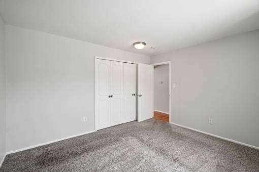A room with grey carpet and white walls with two doors.