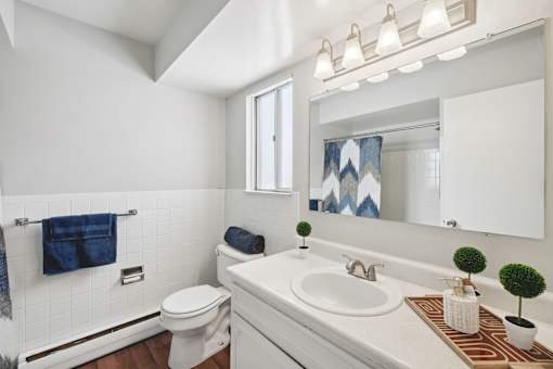 A white bathroom with a toilet, sink, and mirror.