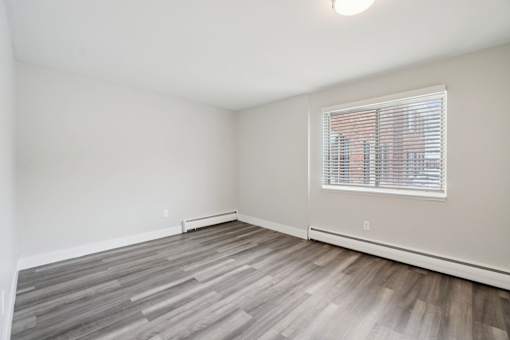 A room with a window and wooden flooring.
