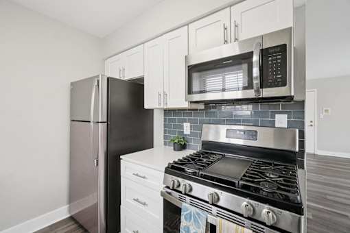 A modern kitchen with a stainless steel oven and black fridge.
