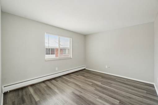 A room with a window and wooden flooring.