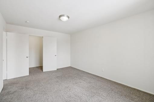 A large empty room with carpeted floor and white walls.