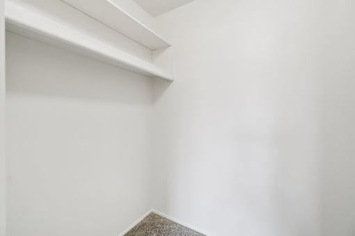 A white shelf in a corner of a room.