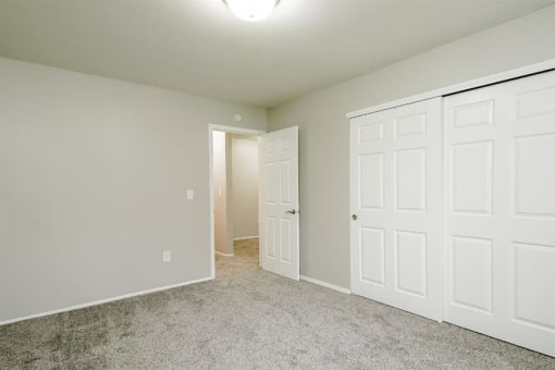 an empty bedroom with two closets and a door