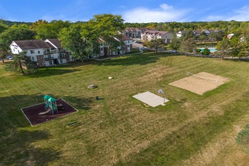 a view of the backyard of a house with a playground and a basketball court