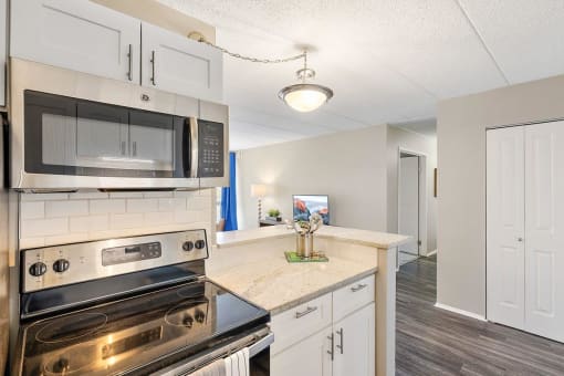 a kitchen with stainless steel appliances and white cabinets at Troy Place Apartments - Troy, MI, Troy