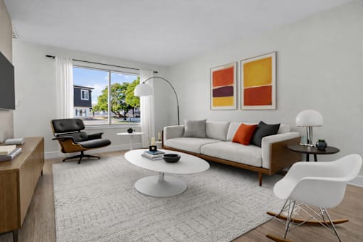 A modern living room with a white sofa, a black chair, a white coffee table, and a white rocking chair.