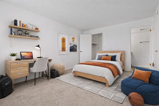 A bedroom with a bed, desk, and chair.