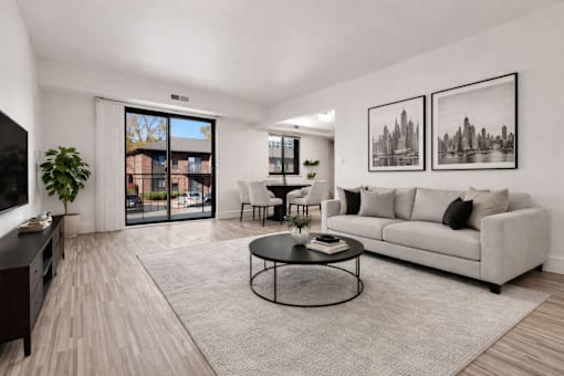 A living room with a grey couch, a coffee table, and two framed pictures on the wall.