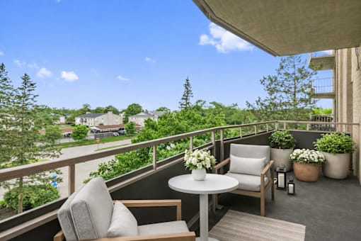 A balcony with a table and chairs overlooking a residential area.