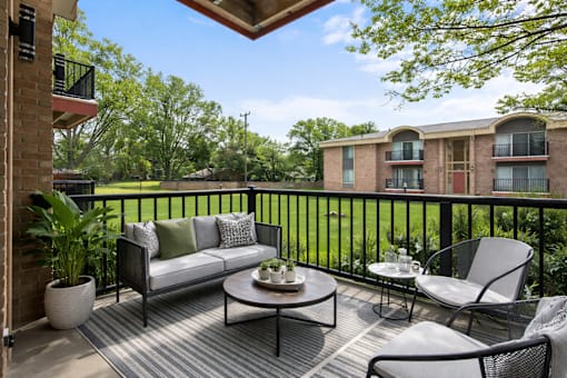 A balcony with a couch, chairs, and a table with a plant on it.