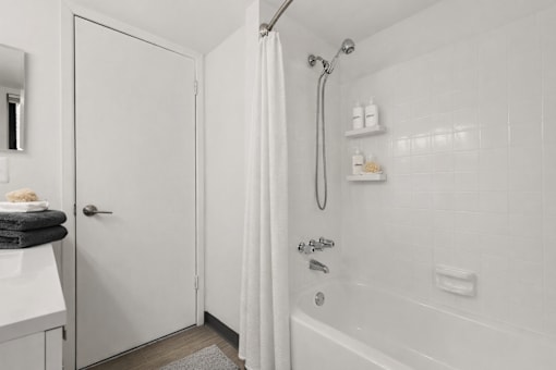 A white bathroom with a shower and a towel on the door.