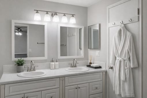 A white bathroom with a white robe hanging on the door.